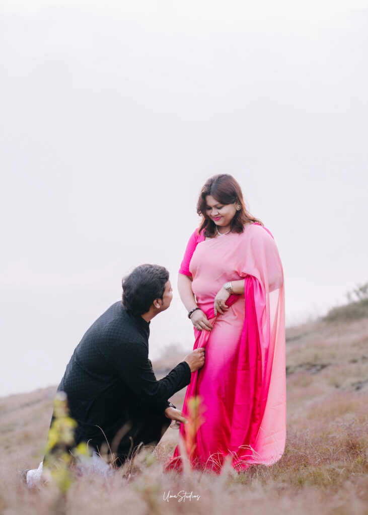 Candid couple photoshoot in Munnar showing a romantic moment with a man adjusting the saree of his partner on a scenic hillside, captured by Uma Studios Munnar